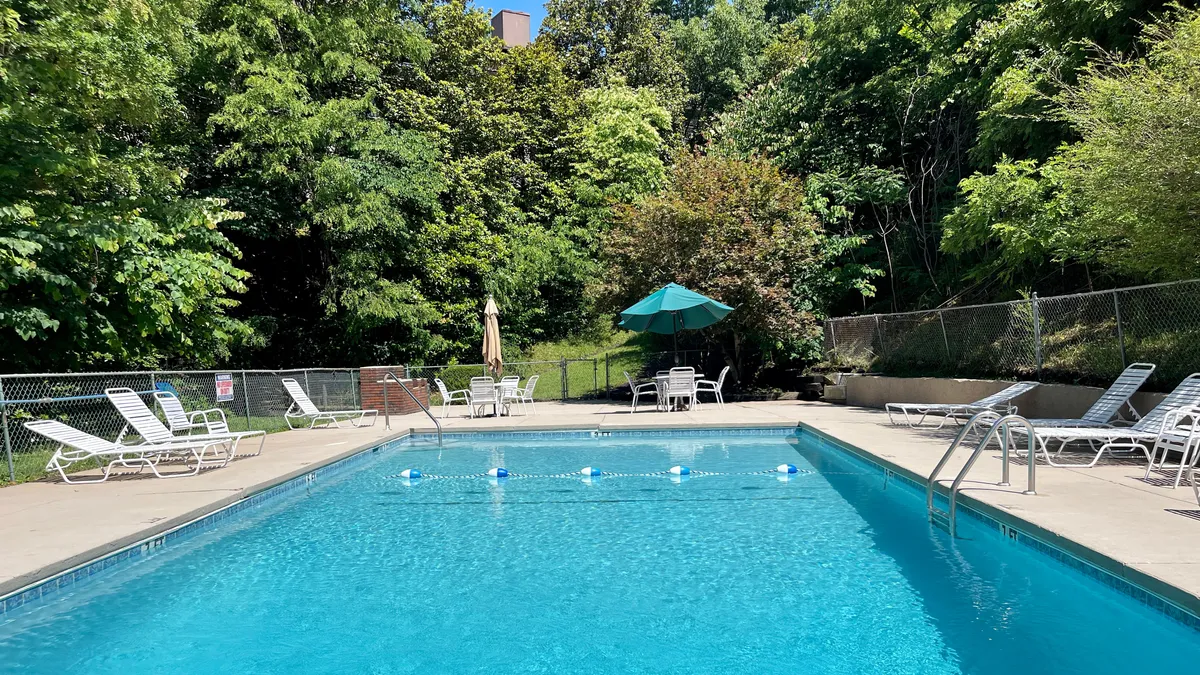 An inviting outdoor swimming pool surrounded by lounge chairs, umbrellas, and greenery. The space appears perfect for morning swims, sunbathing, or relaxing after a productive day.